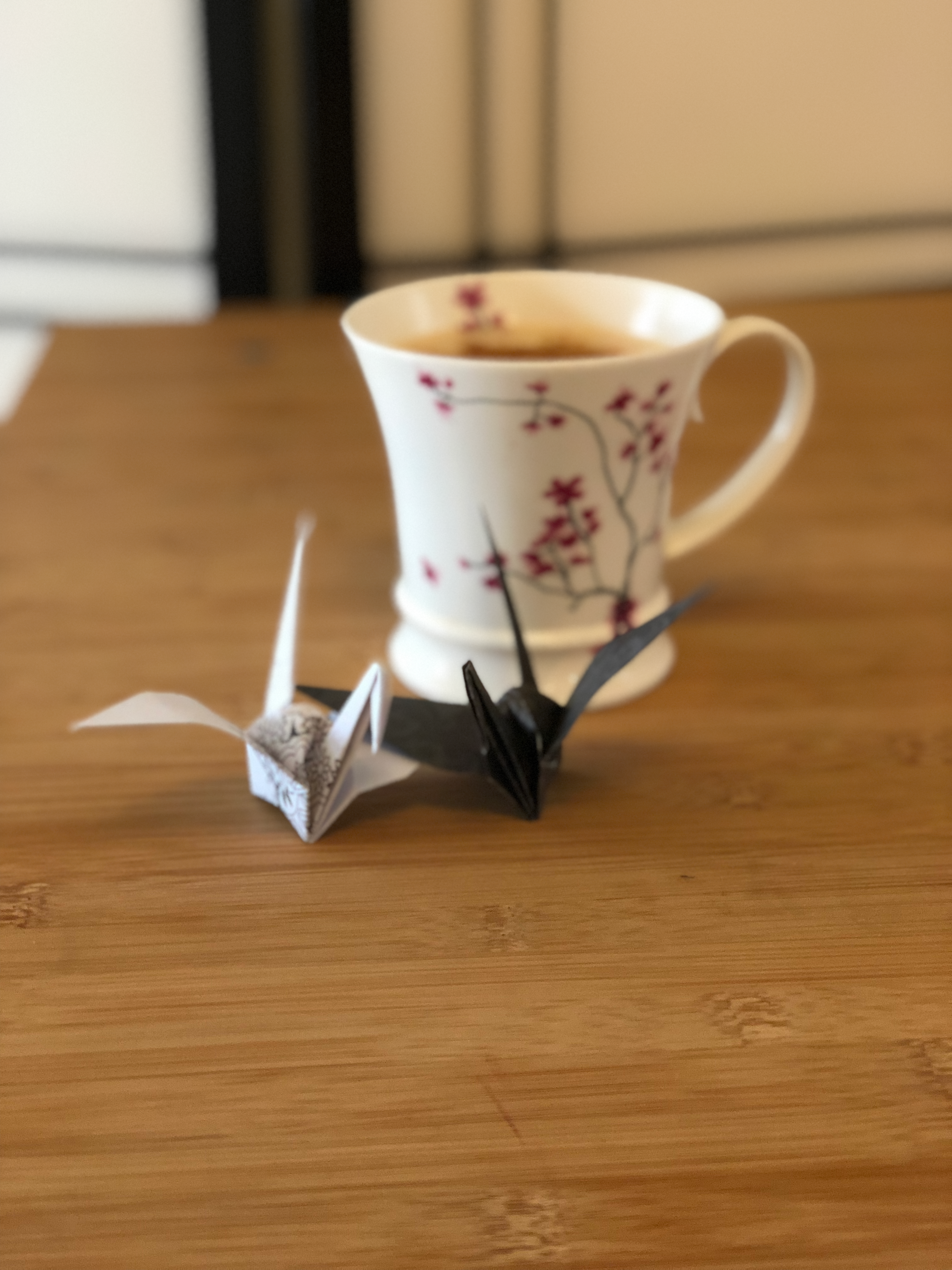 Two small origami cranes and a cup of tea.