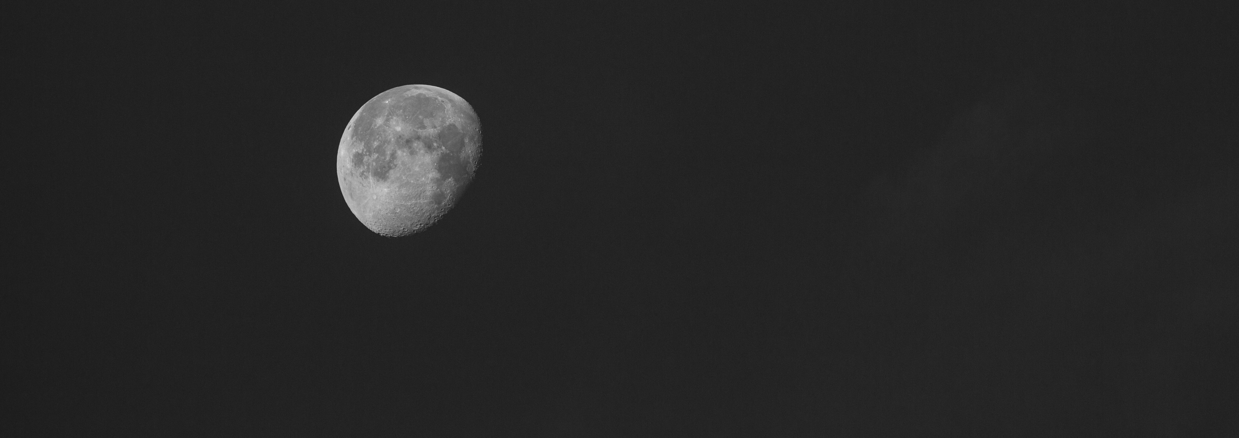A black and white photo of the night sky with an almost full moon.