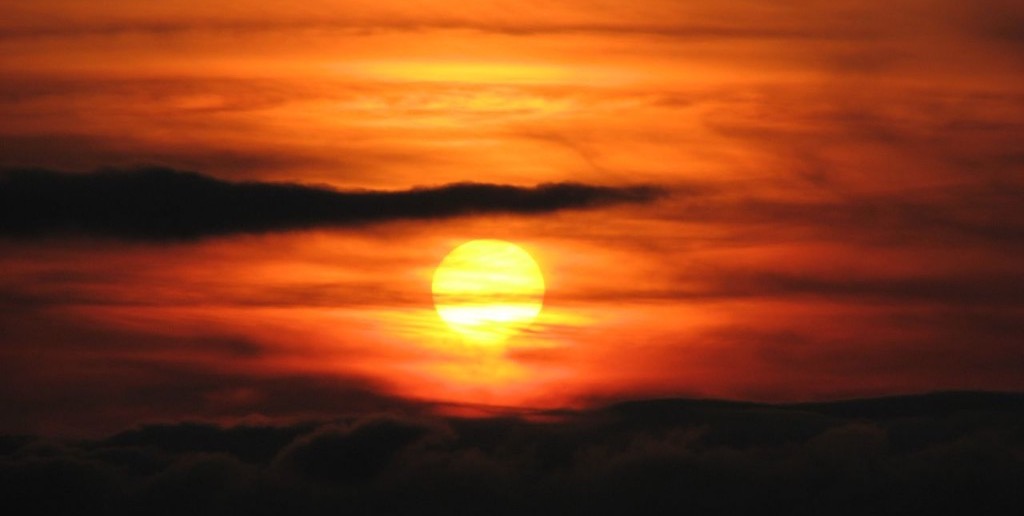 A firey setting sun in a cloudy sky over the mountains surrounding Hakodate Japan.